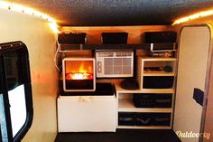 the interior of a tiny camper rental with lights on and an open fire place