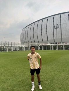 a man standing on top of a lush green field next to a giant soccer ball