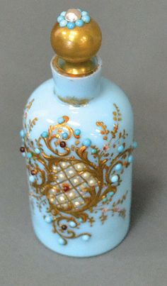 a blue and gold decorated glass bottle on a gray surface with an ornate design in the top