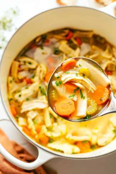 a ladle full of chicken noodle soup with carrots