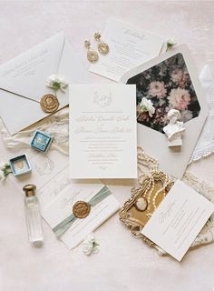 the wedding stationery is laid out on top of each other, including an envelope and ring