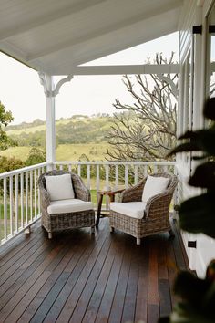 two wicker chairs sitting on top of a wooden deck next to a white roof