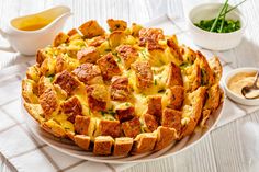 a cheesy bread dish on a plate with dipping sauce