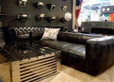 a black leather couch sitting on top of a hard wood floor next to a wooden table