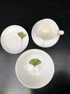 three white plates with green leaves on them