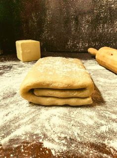 two uncooked pizza doughs sitting on top of a table next to a rolling pin