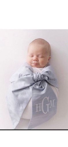 a baby wrapped in a blue blanket with the letter hgm on it's chest