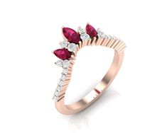 a rose gold ring with three pear shaped ruby and white diamonds on the side, set in