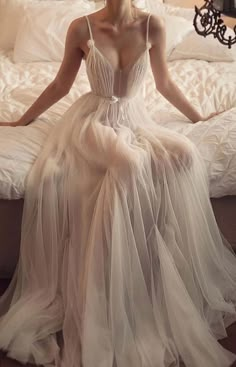 a woman sitting on top of a bed in a white dress