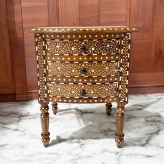 an ornately decorated chest of drawers on marble floor