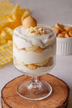 there is a dessert in the glass on top of a tree stump with other food items around it