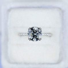 an engagement ring with a diamond on it in a white gift box that is open