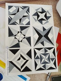 several pieces of paper with black and white designs on them, next to some paintbrushes