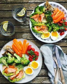 two plates filled with different types of food on top of a wooden table next to utensils