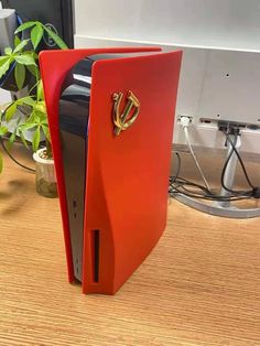 an open red computer case sitting on top of a wooden desk next to a plant