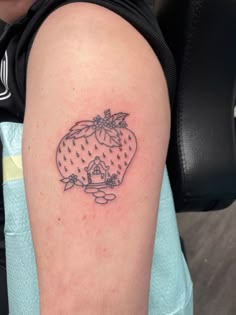 a woman with a strawberry tattoo on her left arm and the outline of a house in the background