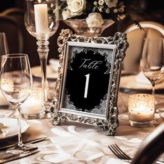 the table is set with candles, wine glasses and an ornate silver framed photo frame