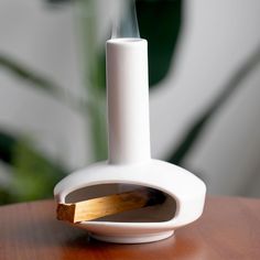 a white candle holder sitting on top of a wooden table next to a potted plant