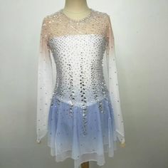 a white and blue dress with sequins on the top is sitting on a mannequin