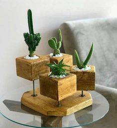 three succulents are placed in wooden blocks on top of a glass table