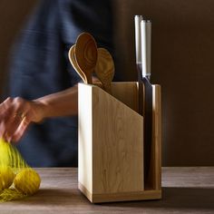 a person is cutting up some food with wooden utensils and spoons in a holder