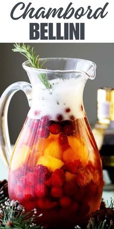 a pitcher filled with fruit and ice sitting on top of a table next to pine cones