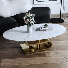 a living room with a black couch and white marble coffee table in the middle,