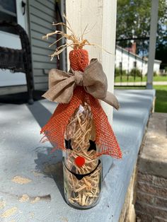 a glass bottle with straw wrapped around it and a scarecrow face on the front