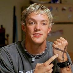 a young man with blonde hair wearing a cross necklace