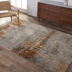 a large rug in the middle of a room with a chair and cabinet behind it