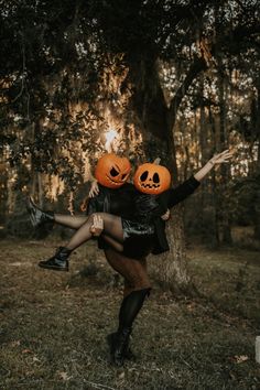 two people dressed up as jack - o'- lanterns are holding each other in the air