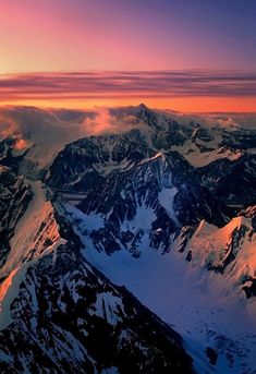 the sun is setting over some snowy mountains