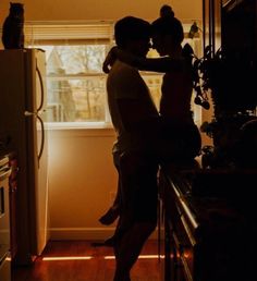 a man and woman standing in front of a window next to a refrigerator freezer