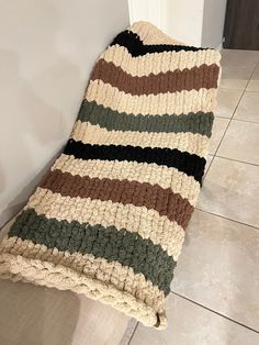 a crocheted blanket sitting on the floor next to a white door and tiled floor