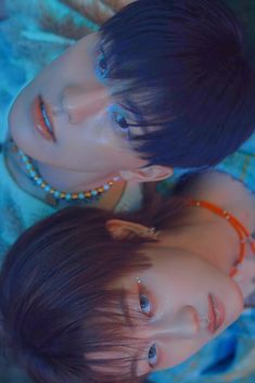 two young women laying on top of each other in front of a blue blanket and wearing necklaces