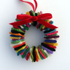 a colorful wreath with a pink ribbon hanging from it's side on a white surface