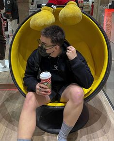 a man sitting in a chair with two stuffed animals on his head and holding a drink