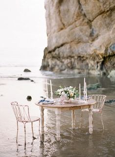 a table and chairs are set up in the water at the beach for an outdoor dinner