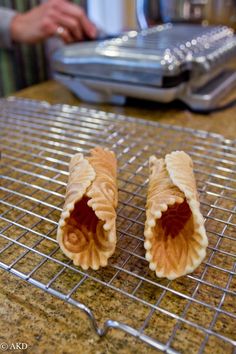 two pastries sitting on top of a cooling rack next to a person's hand