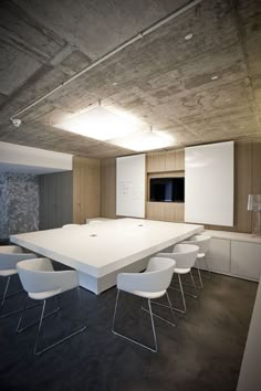 an empty conference room with white chairs and a large table in the center, surrounded by wooden paneling