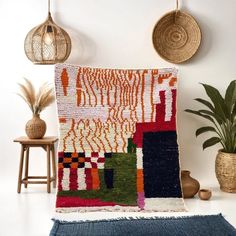 a colorful rug is hanging on the wall next to a potted plant and two wicker baskets