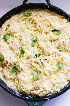 a skillet filled with pasta and topped with basil