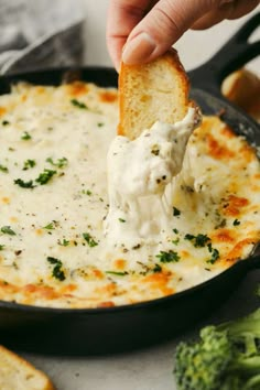 a person dipping cheese onto bread with broccoli in the foreground and on the side