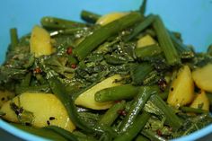 a blue bowl filled with green vegetables on top of a table