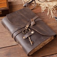 an old book with a key on it and eyeglasses next to the book