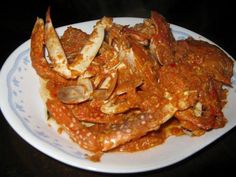 a white plate topped with cooked crabs covered in sauce