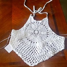 a white crocheted doily on a wooden floor with a string attached to it