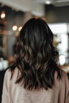 Woman with wavy, dark brown hair facing away in a softly lit room. Cool Brown Highlights, Highlights Color Ideas, Short Dark Brown Hair With Highlights, Mocha Highlights, Dark Brown Hair With Caramel Highlights, Black Hair With Brown Highlights, Hair With Brown Highlights, Highlights Hair Color Ideas, Highlights On Black Hair