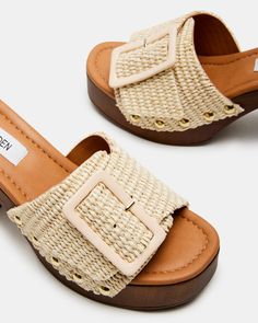 Step out in style with MARLENA! These unique sandals feature a wood block heel and platform for comfortable height, while the mule design adds a touch of elegance. The oversized buckle detail gives a playful twist to the classic resort look! 3.75 inch heel height 1.5 inch platform Raffia upper material Synthetic lining Synthetic sock Synthetic sole Imported Trendy Mules With Wooden Block Heel, Chic Beige Heels For Summer Outings, Trendy Buckle Closure Wedge Sandals For Vacation, Summer Mules With Wooden Block Heel, Chic Beige Open Heel Clogs, Casual Natural Heels With Wooden Heel, Summer Mules With Wooden Heel, Trendy Open Heel Slides For Vacation, Casual Heels With Wooden Heel In Natural Color