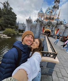 a man and woman taking a selfie in front of a castle at disneyland world